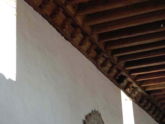 Interior detail view showing cornice wood molding between plaster wall and wooden ceiling