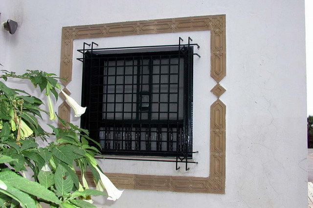 Exterior detail, lower window with grill and decorative frame