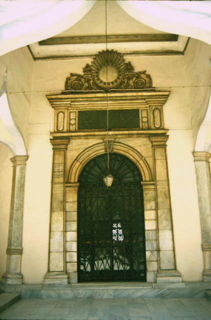 The entrance to the mausoleum seen from under the wooden arch of the courtyard portico The marble frame of the door reflects the period architecture of Sultan Abdülaziz