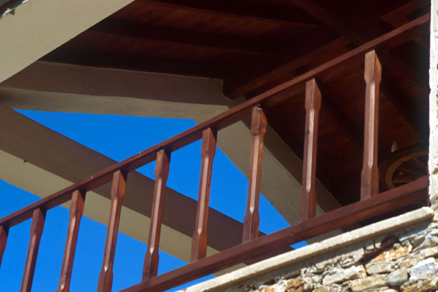Exterior detail showing wood banister and underside of pitched roof