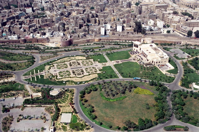 Aerial view of park looking west at the Hilltop Restaurant, preceded by formal gardens. The Darb al-Ahmar neighborhood is seen behind the Ayyubid city walls
