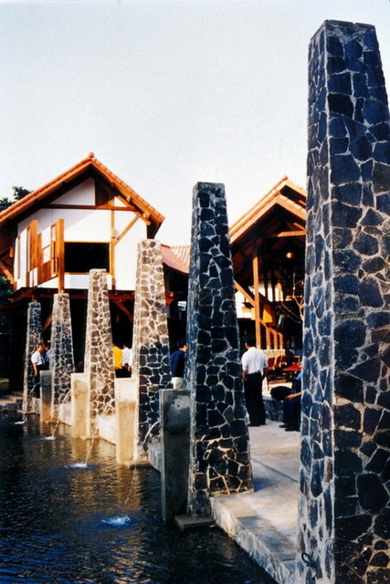 Exterior view, with wooden walkway flanked by stone pillars
