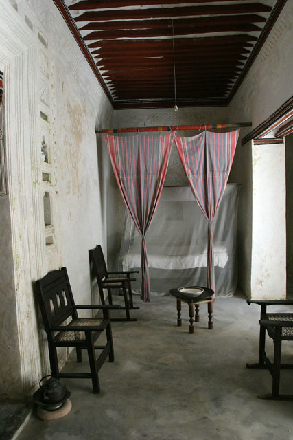 Interior view of sleeping area with Swahili chairs and canopied bed