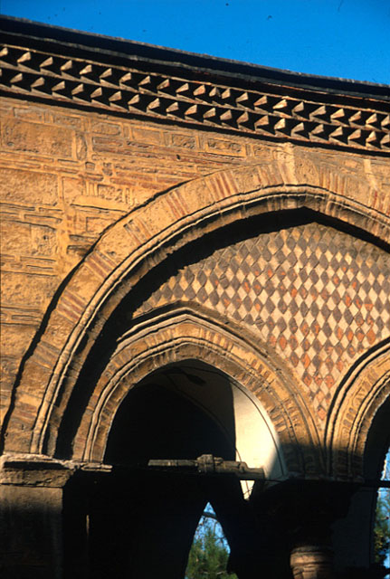 Exterior detail from end arch of mosque portico on the east, showing ornamental brickwork of cornice and façade and a Byzantine capital on the lower right