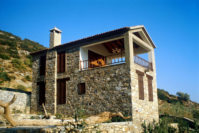 Exterior view showing stone house with upper level balcony