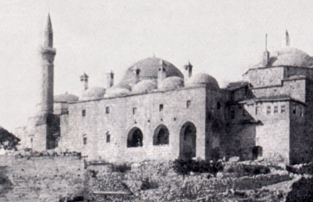 Exterior view from northwest showing the entrance, with dervish cells above. The minaret of the mosque appears on the left, while the dome of the kitchen (asevi) is seen at right and The large dome seen behind the  domes of the dervish cells belongs to the Battal Gazi Tomb