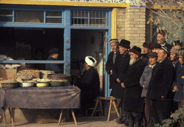 People beside dry goods store along east elevation of mosque