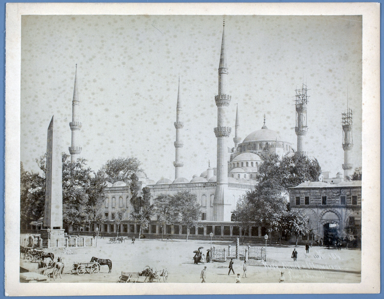 Western view of the mosque, with the western gatehouse to the right and the Obelisk of Theodosius in the ancient Hippodrome in the foreground. "N. 104. Mosq. Ahmed &amp; Hippodrome."
