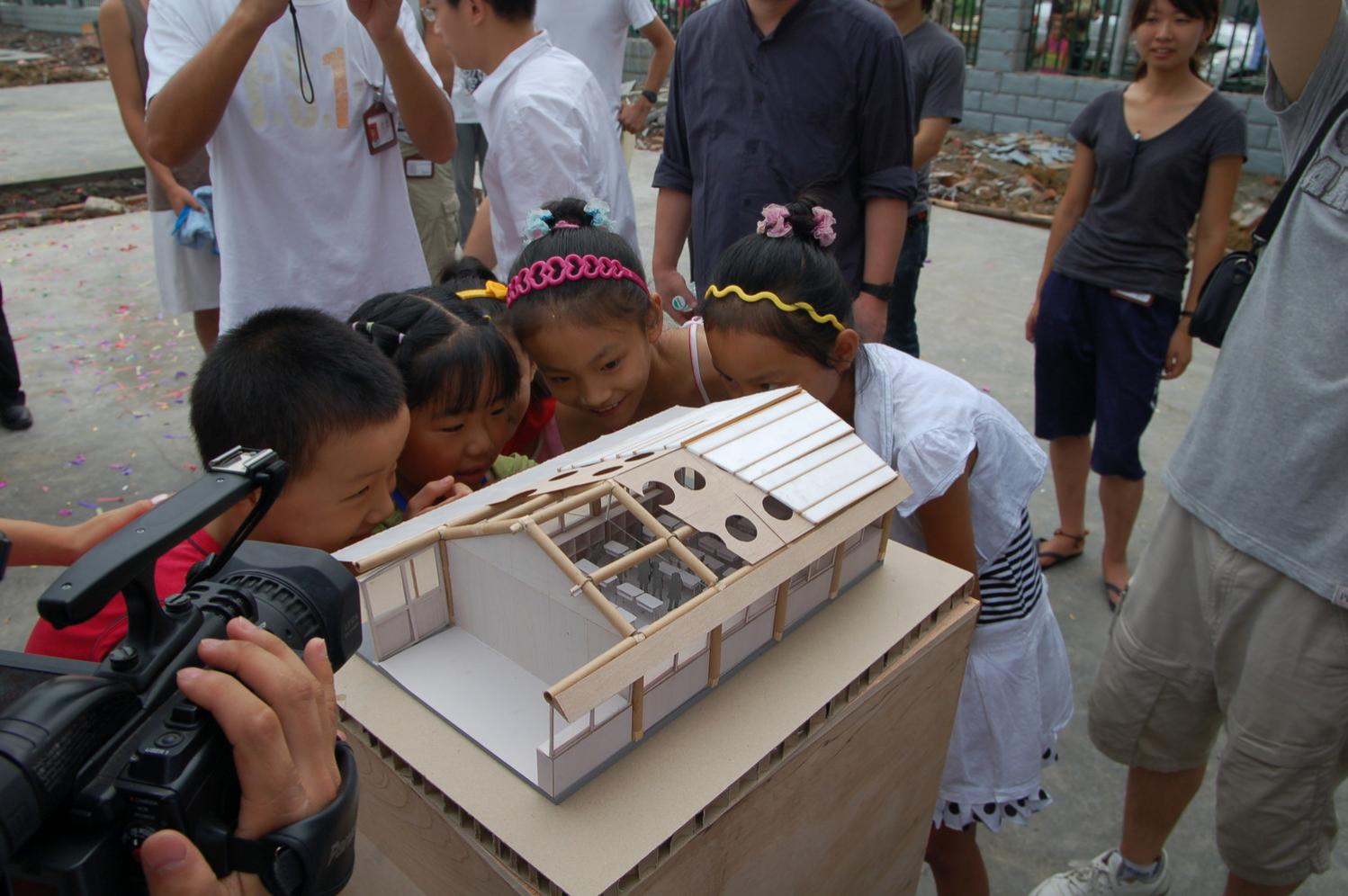 Children looking at the model of the classroom before construction