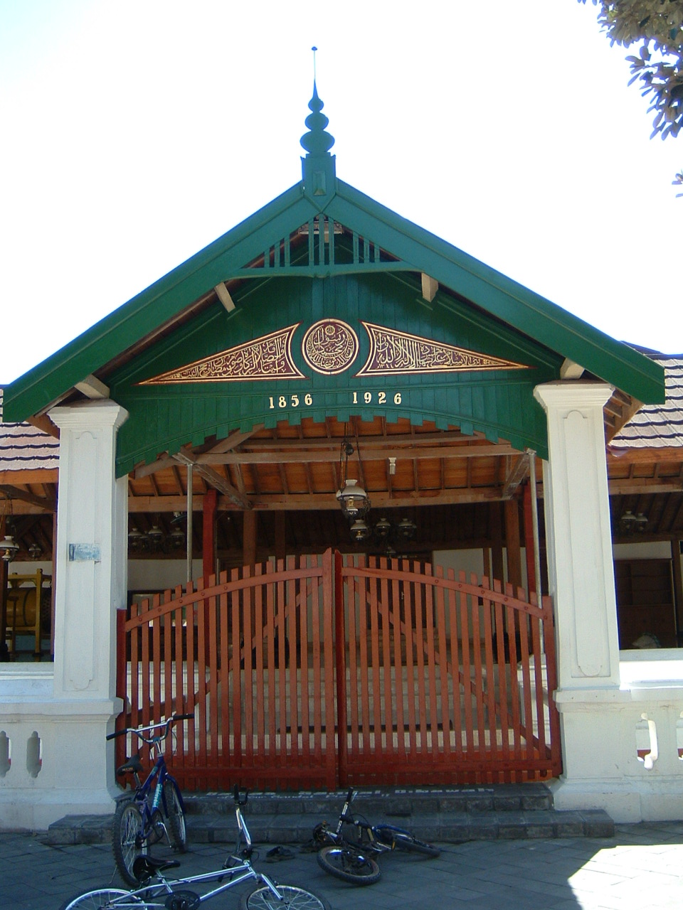 Exterior view showing the mosque entry gate with Arabic inscription on gable