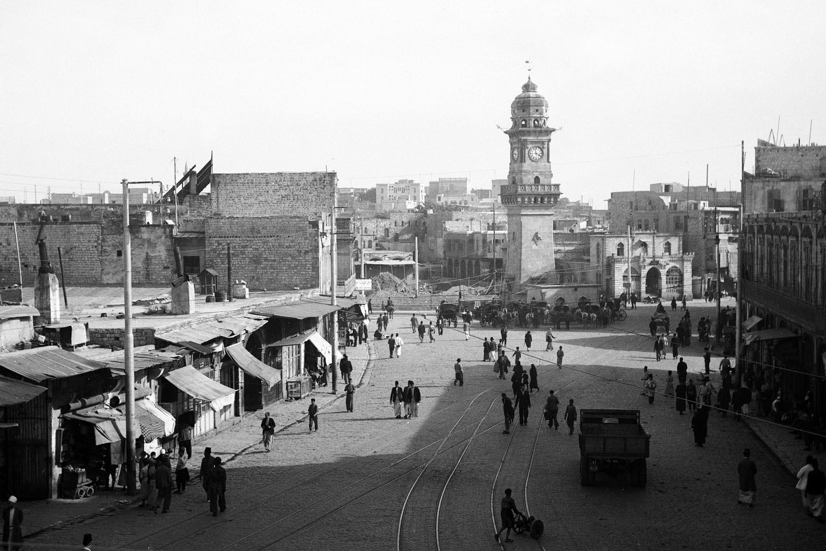 Section of public square known as Bab al-Faraj seen in 1937, part of the surrounding fabric of the gate demolished in 1904. Clock tower built in 1898-1899 by the Austrian architect of Aleppo city Charles Chartier with the help of the Syrian engineer Bakr Sidqi, under the Ottoman ruler of Aleppo; wāli Raif Pasha