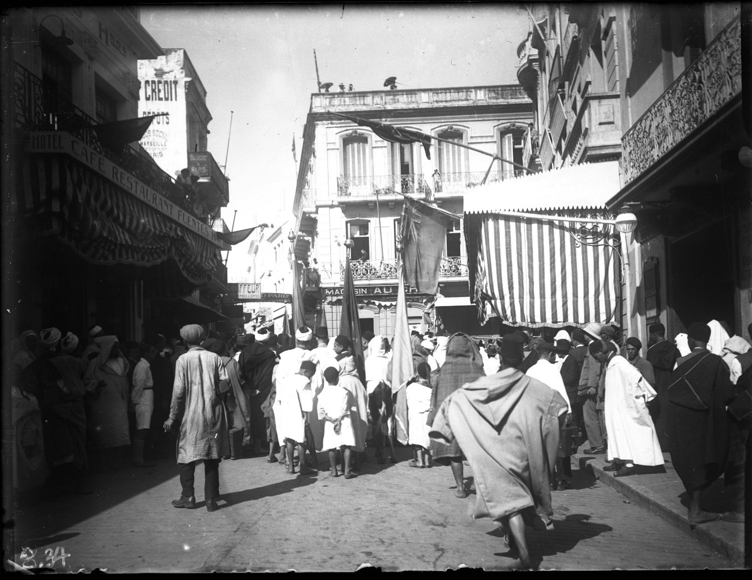 Street scene of Le Petit Socco toward Bab Fahs; crowd of adults and children in Moroccan dress  