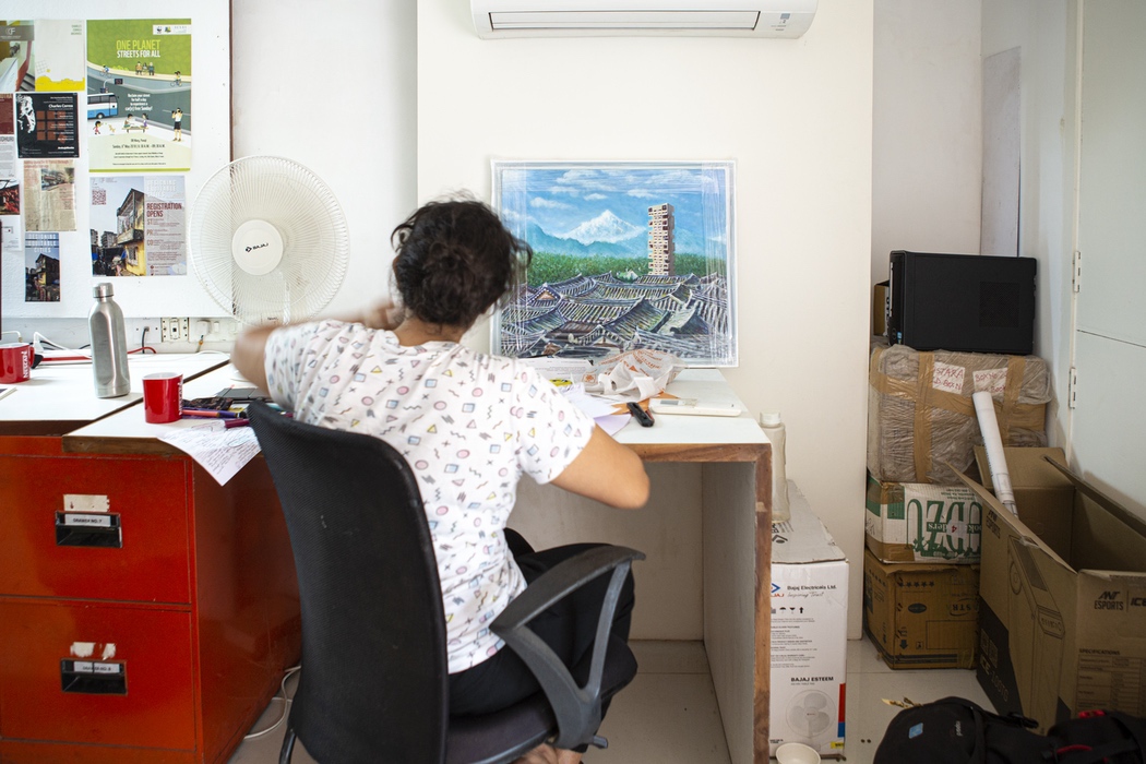 <p>A visitor at the desk with an imaginative painting of Kanchenjunga building in South Korea</p>
