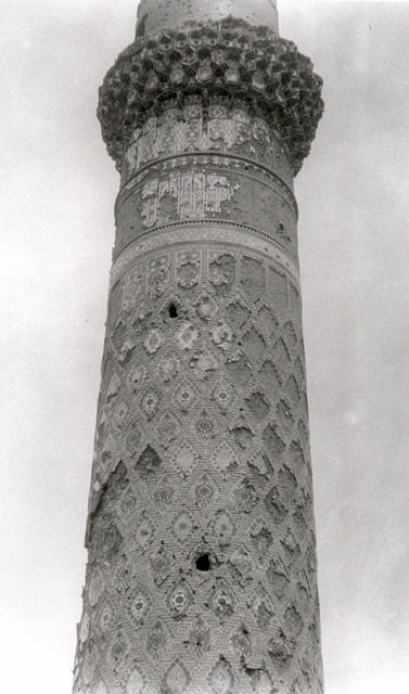 Madrasah-i Gawhar Shad - Detail of the remaining minaret of the Gawhar Shad Madrasa, showing central portion of shaft with diamond-patterned tile ornament and muqarnas base of balcony