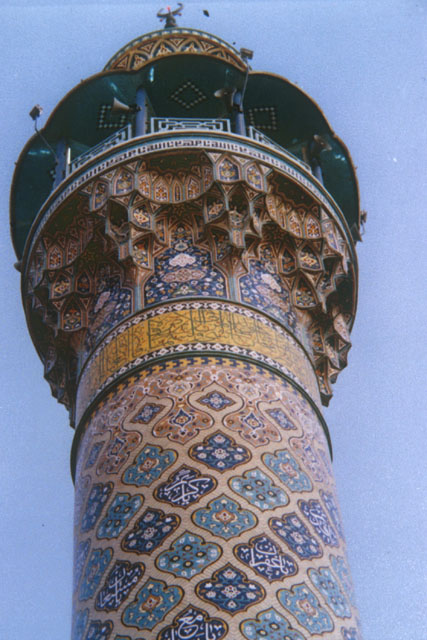 Exterior detail showing carved muqarnas decoration below balcony of elaborate tiled minaret