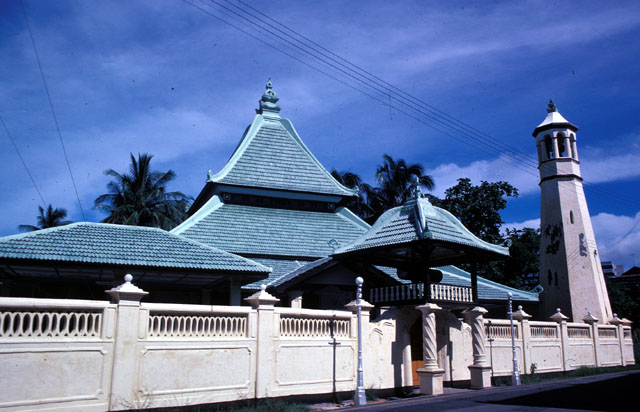 Masjid Kampung Hulu from Jalan Kampung Hulu (Kampung Hulu Road) facing west, roof of ablution pool at left, roofs of mosqe and entry gate and minaret at left