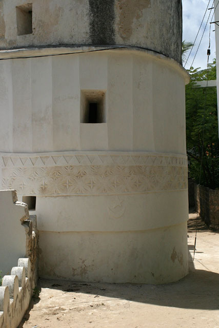 Exterior view looking at base of minaret showing decorative band of external plasterwork with star and crescent detail
