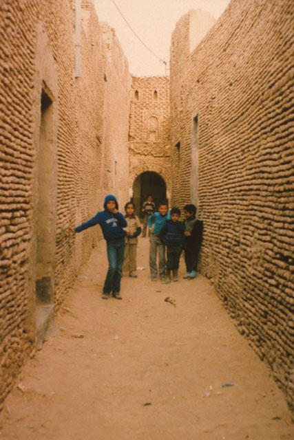 Exterior view along narrow path between brick walls