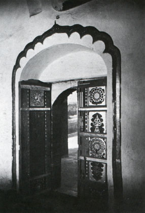 Highly decorated door of prayer hall sits in arched recessed entryway