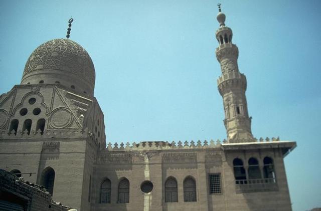 Exterior view, upper zone of façade, mausoleum with carved stone dome and minaret