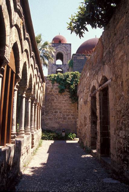 View of corridor next to monastery cloister (left), with bell tower of the church seen in the background