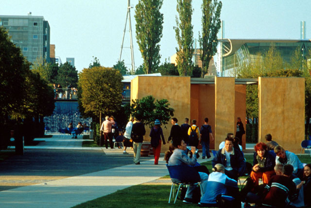 Exterior view through park setting showing seating and partitions and landscaping