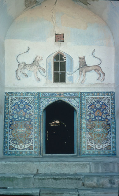 View of iwan with arched doorway topped with depictions of lions