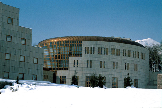 Exterior view showing circular main building against mountainous backdrop