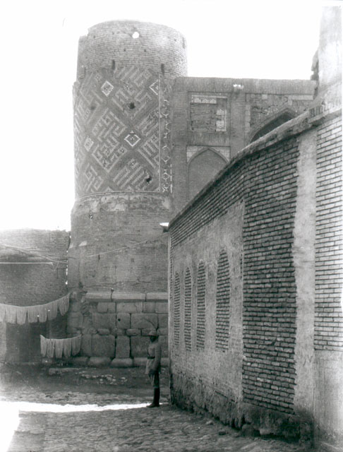 Exterior view from street showing tiled minaret rising behind portal