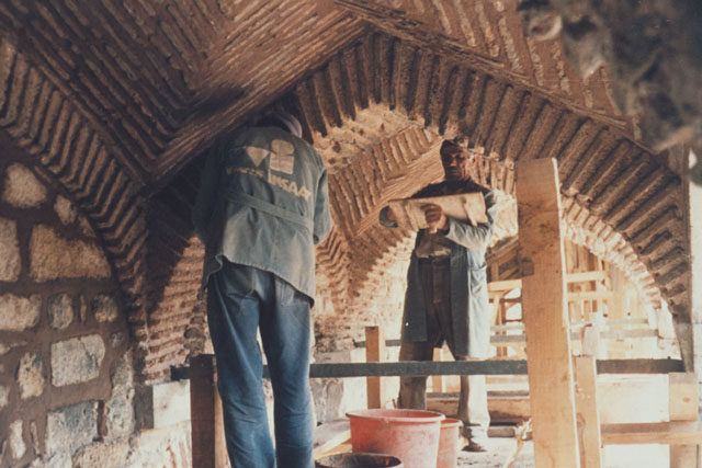 Interior detail showing laborers finishing brickwork of arches