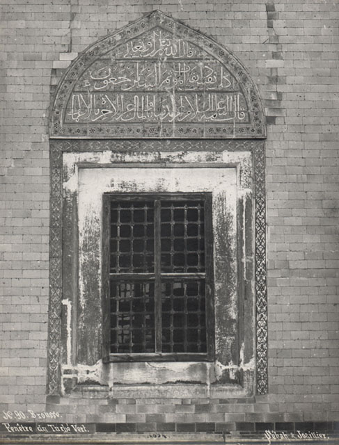 View of window on the exterior, showing floral tile border and tiles with Koranic inscriptions decorating the tympanum