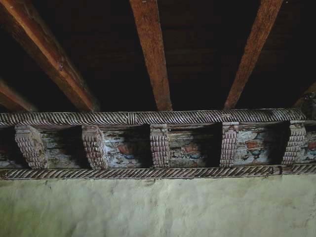 Interior detail of cornice transition between side wall and wood rafter ceiling showing remnants of paintings between cornice members