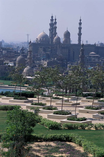 View of marble terrace with tree planters, looking south. The domes and minarets of Sultan Hasan and Al-Rifa'i Mosques are silhouetted in the background, while the Khayrbak Complex and Amir Aqsunqur Mosque are seen at center in the Darb al-Ahmar neighborhood