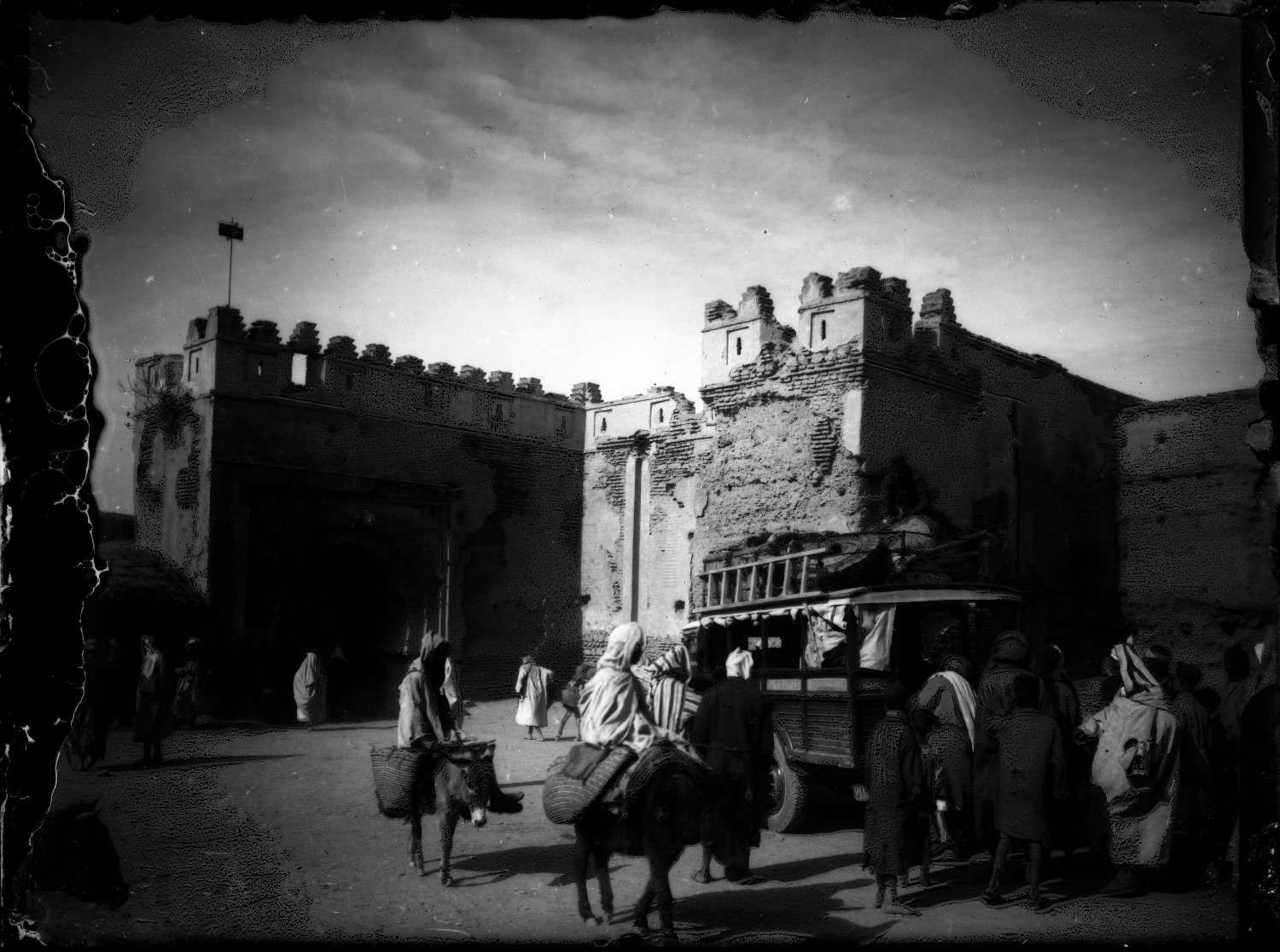 People in traditional garb with automobiles and donkeys in front of Bab Ghmat.