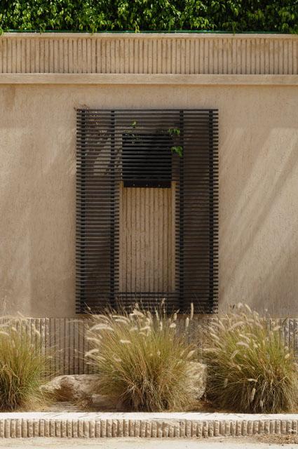Exterior walls in plastering finish, decorated with traditional crafts like metal screens, inviting local culture in this contemporary building