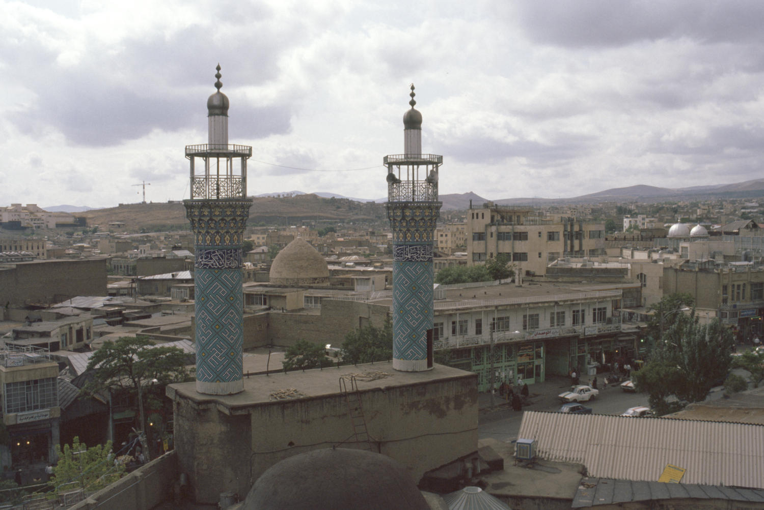 View of minarets above entrance portal, with Hamadan cityscape in distance.