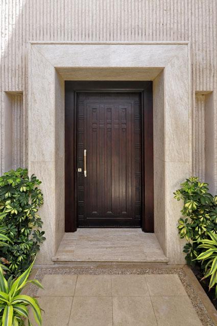 detailed view of the main entrance wooden door, surrounded by marble cladding