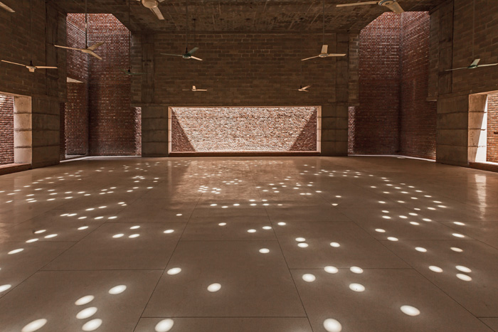 Column free prayer hall is raised on eight peripheral columns, in addition to four light courts, random circular roof openings allows daylight into the prayer hall creating an ornate pattern on the floor enhancing spirituality through light 