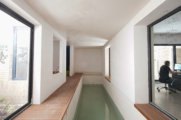 <p>A narrow indoor pool on the basement floor adjoining a courtyard (left) and a living/working space (right).&nbsp;</p>
