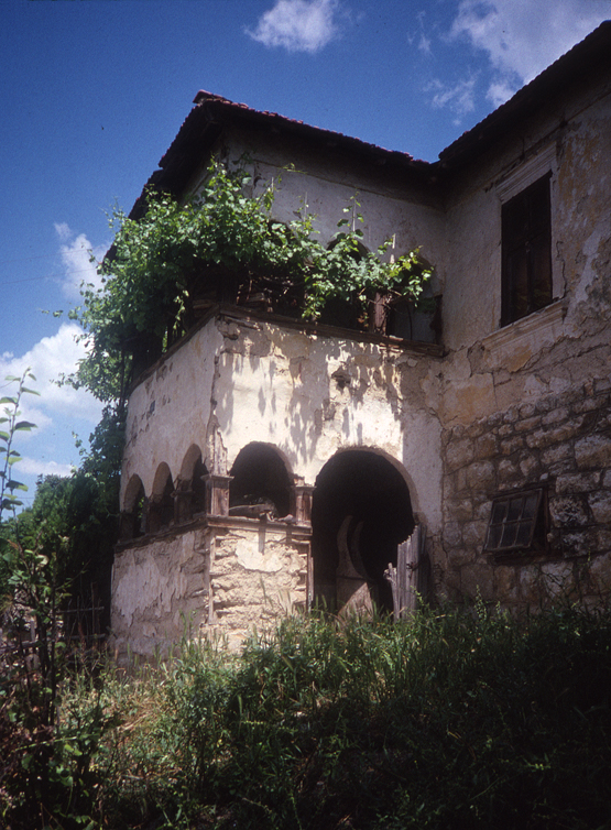 <p>The base of the main portion of the dwelling is constructed using coursed stonework. The lower level čardak space rests on a low stone base. The vines climb the northwest side of the čardak and continue along the west side and south side beyond. The čardak element is timber framed with wattle and daub and a plaster coating. The upper-level window head on the main portion of the dwelling is covered with a projecting plaster articulation to represent a masonry lintel.</p>