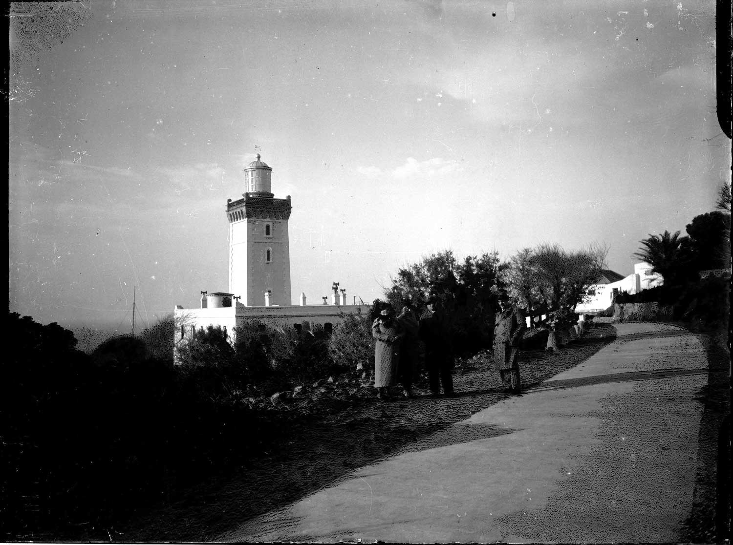 Group of four in Western clothing viewed form the road in front of the lighthouse