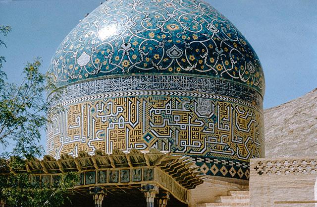Detail view from sanctuary showing the ceiling of portico with wooden cornice, drum with hazarbaf epigraphic band, and dome with tile decoration in floral designs similar to the dome of the Shah Mosque in Isfahan