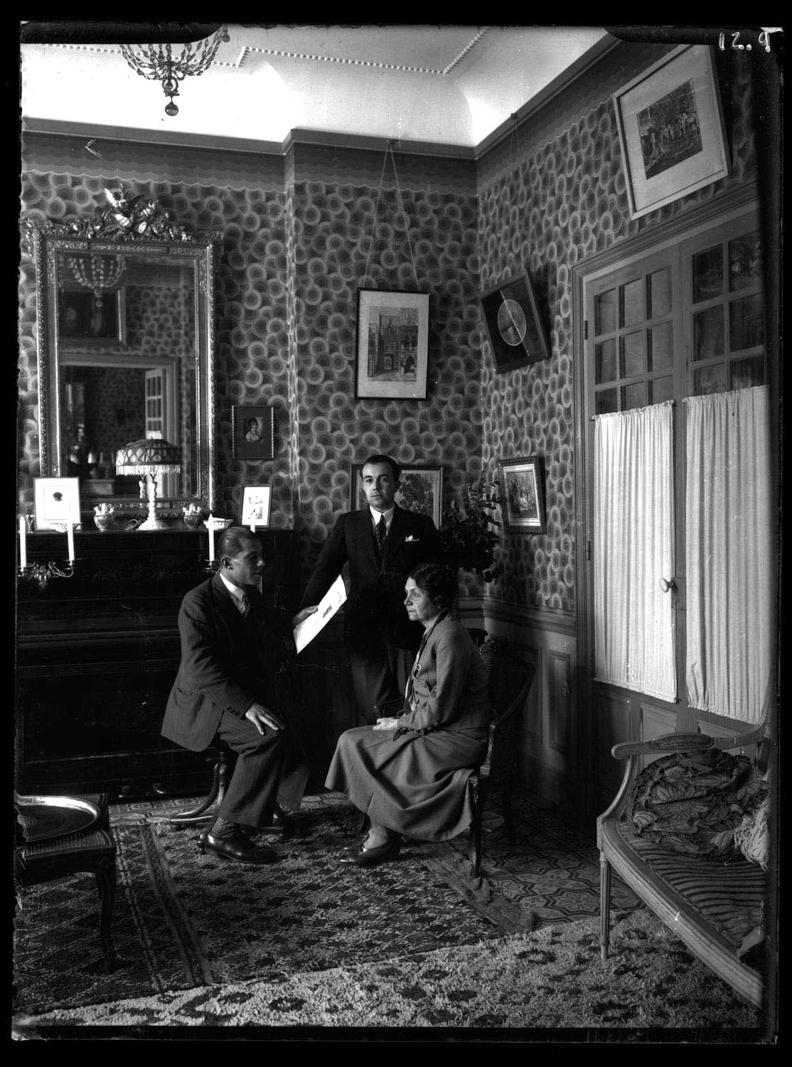 Family portrait of two men and woman in European dress, interior of an elaborately decorated room