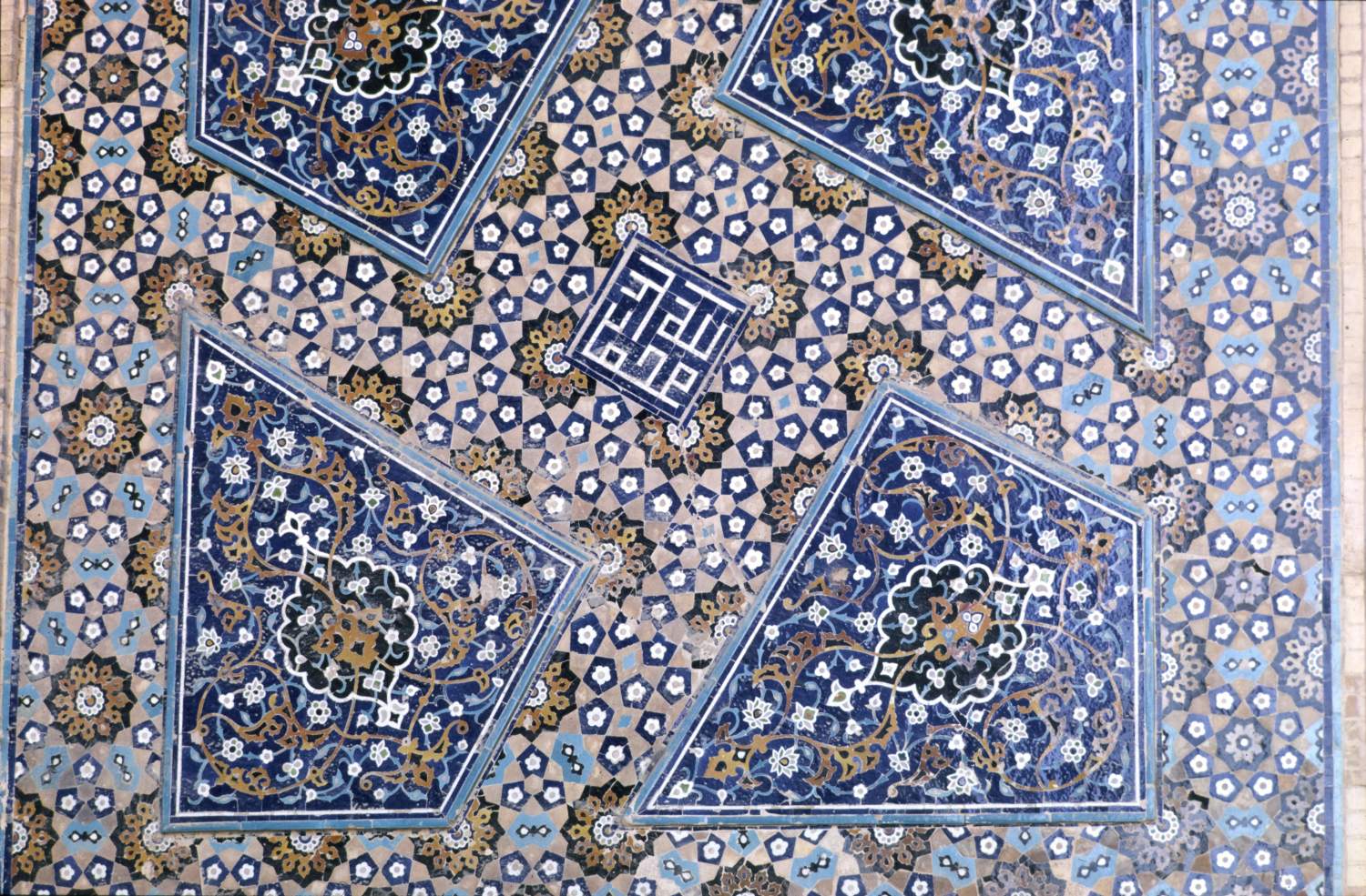Detail of tile mosaic ornament on facade in courtyard, featuring geometric pattern.