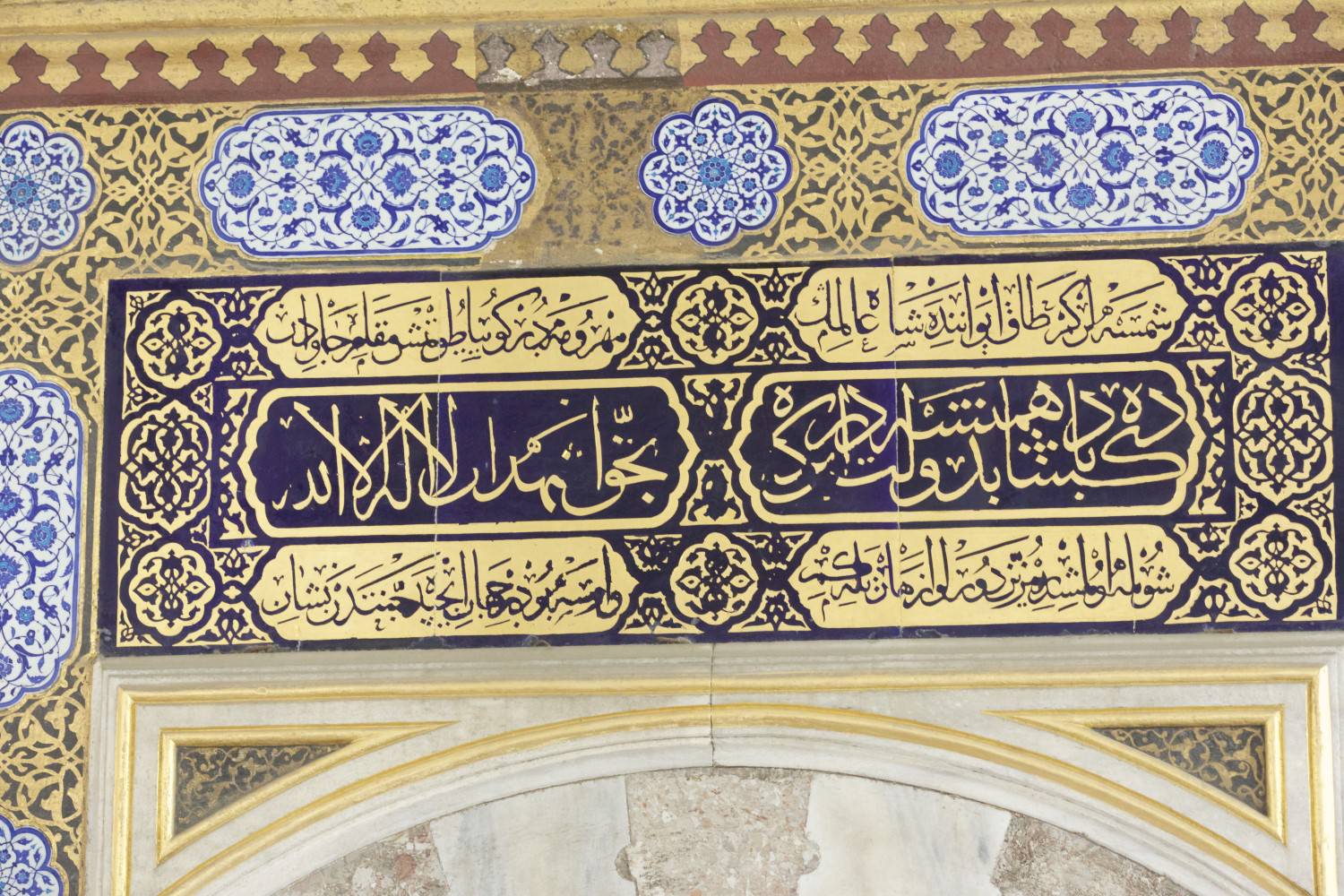 Inscription in black and gold above the entrance, embellished by blue and white tiles with floral design