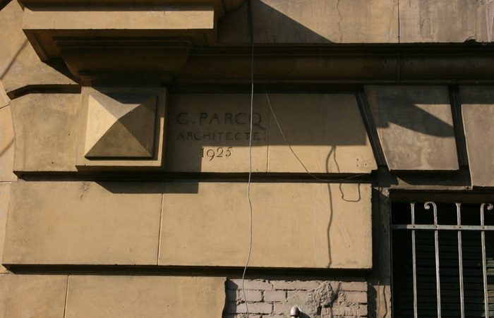 Detail view of the name of the architect and brick masonry rendered with coat and paint, simulating natural stone and forming a regular bond
