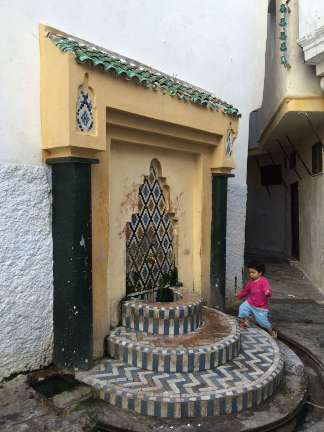 View of a child approaching the decorated fountain to the right of the entrance.